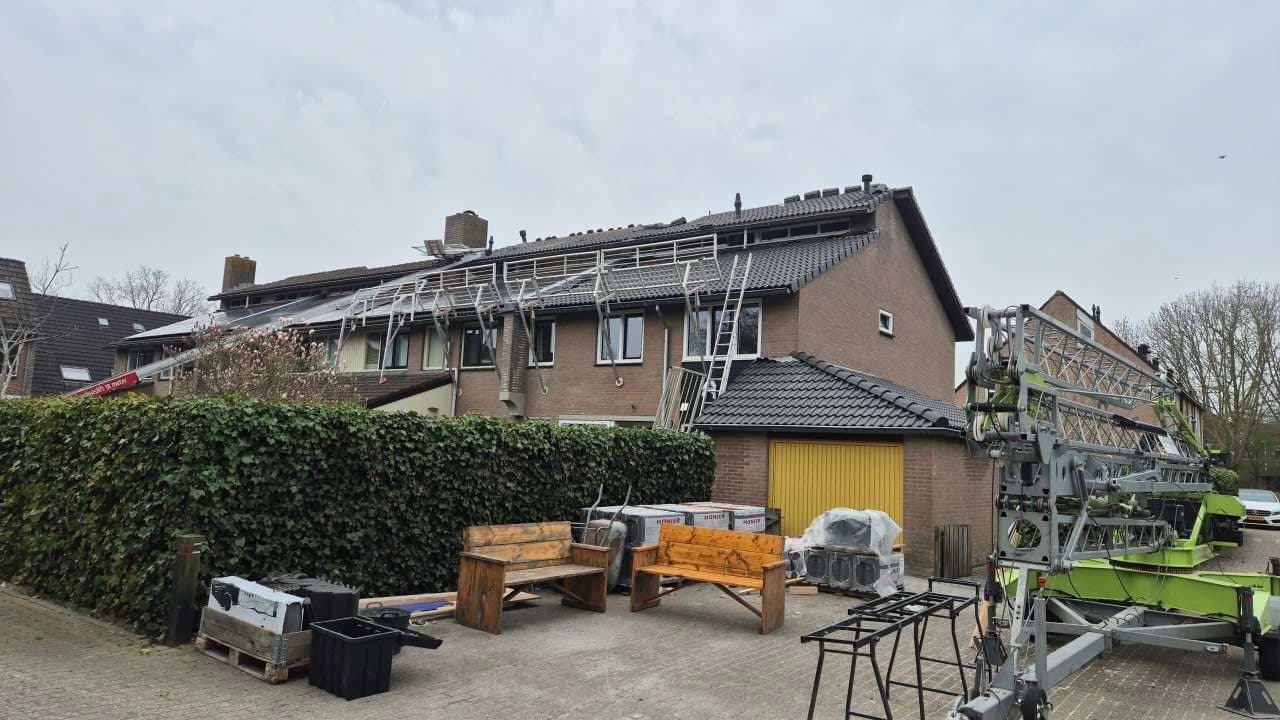 Dakdekker plaatst nieuwe dakpannen op hellend dak in Groningen